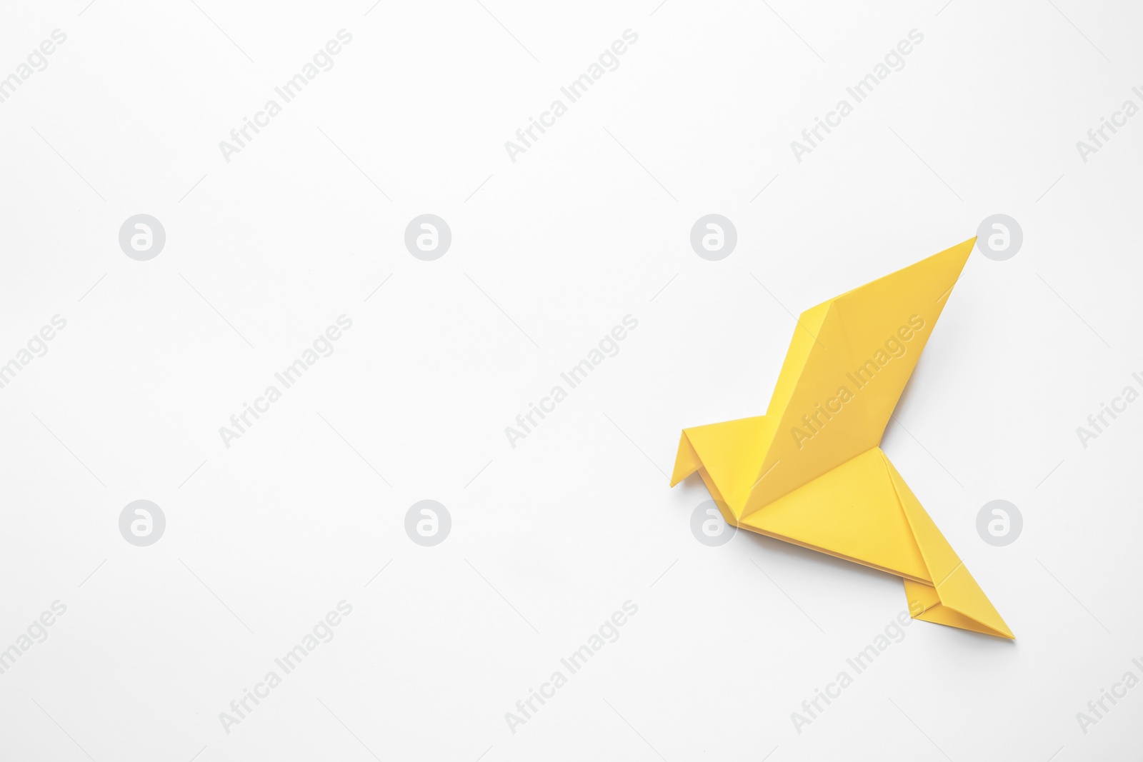 Photo of Beautiful yellow origami bird on white background, top view. Space for text