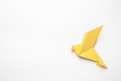 Photo of Beautiful yellow origami bird on white background, top view. Space for text