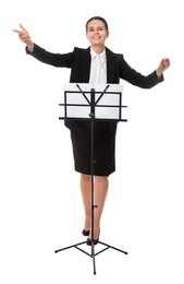 Happy young conductor with baton and note stand on white background