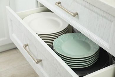 Photo of Stacks of clean plates in drawer indoors