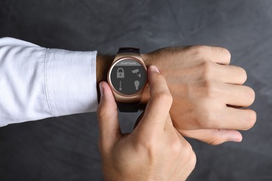 Image of Young man checking electronic wristwatch with Smart Home Interface on grey background, closeup
