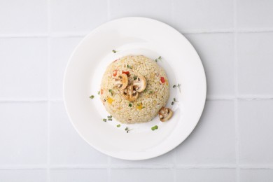 Photo of Delicious bulgur with vegetables, mushrooms and microgreens on white tiled table, top view