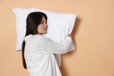Photo of Young woman sleeping on soft pillow against beige background, space for text