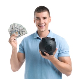 Handsome young man with dollars and piggy bank on white background