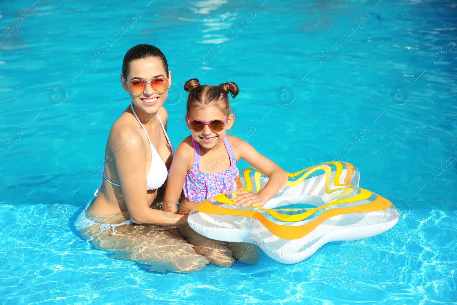 Photo of Young mother with little daughter in swimming pool on sunny day