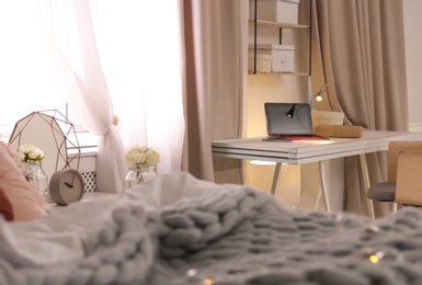 Photo of Workplace with laptop and bed in stylish apartment. Room interior