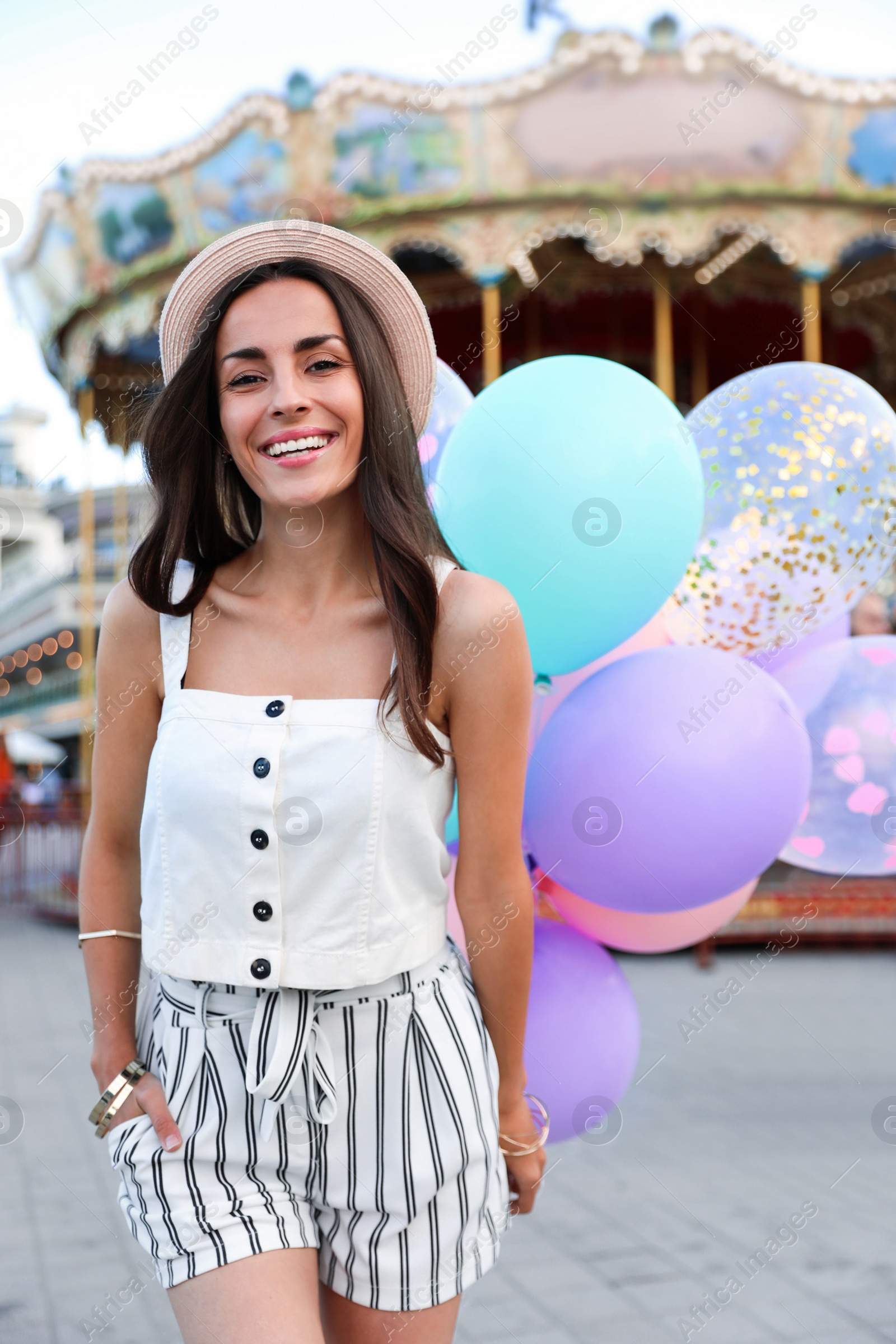 Photo of Attractive young woman with color balloons near carousel