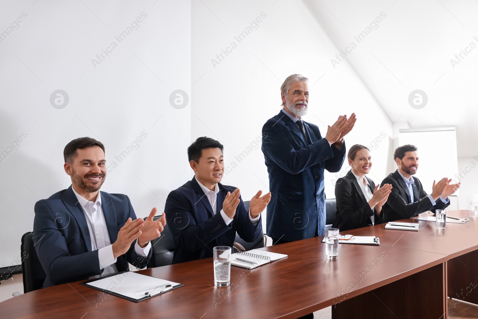 Photo of Business conference. People in meeting room applauding to speaker report