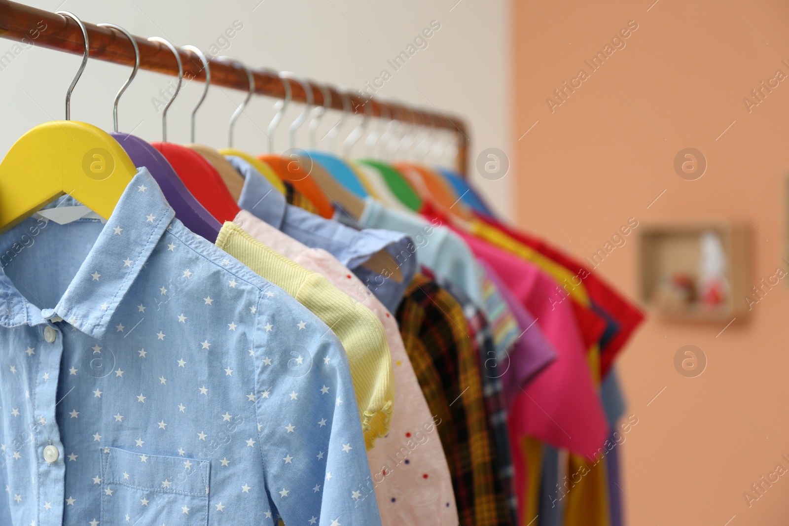 Photo of Different child's clothes hanging on rack indoors, closeup