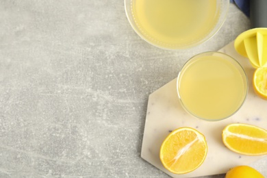 Photo of Freshly squeezed lemon juice on grey marble table, flat lay. Space for text