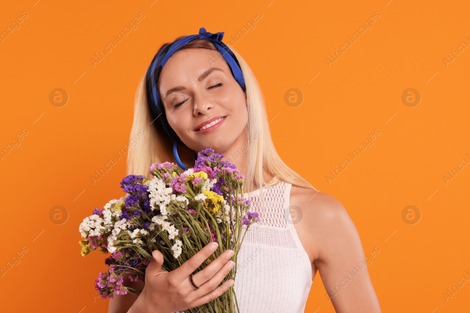 Photo of Happy hippie woman with bouquet of flowers on orange background
