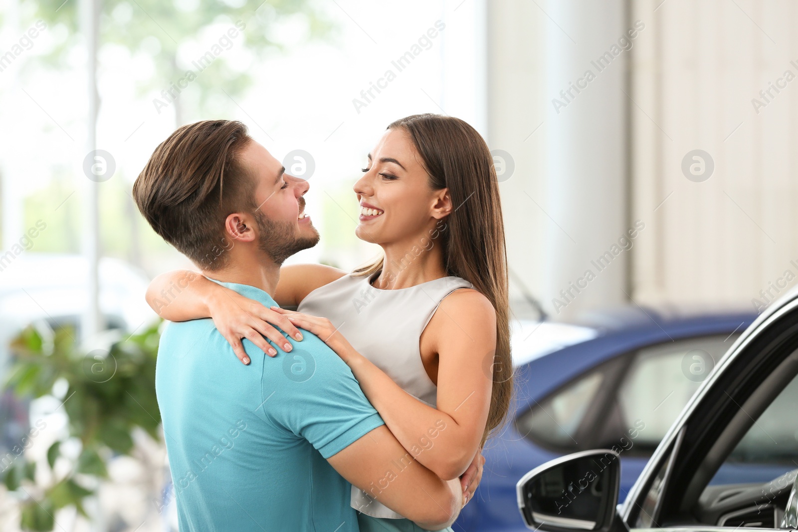 Photo of Happy couple buying new car in salon