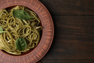 Photo of Tasty pasta with spinach on wooden table, top view. Space for text