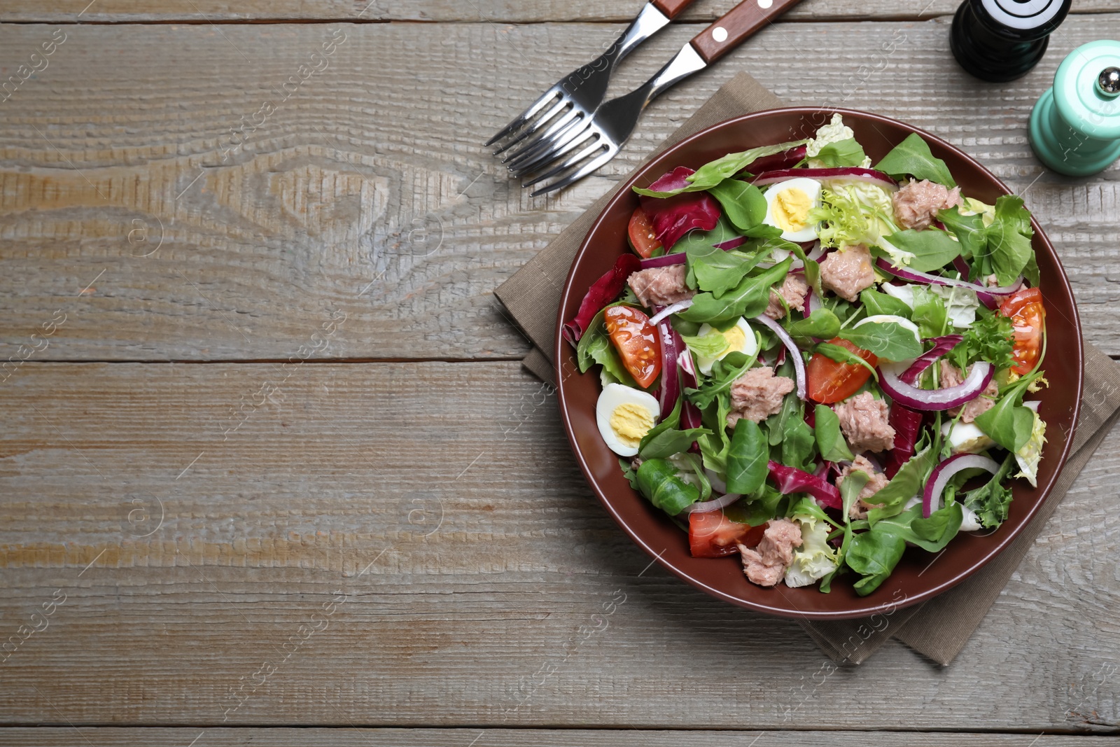 Photo of Bowl of delicious salad with canned tuna and vegetables served on wooden table, flat lay. Space for text