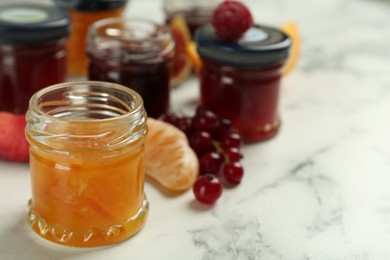 Photo of Jar of sweet jam on white marble table, closeup. Space for text