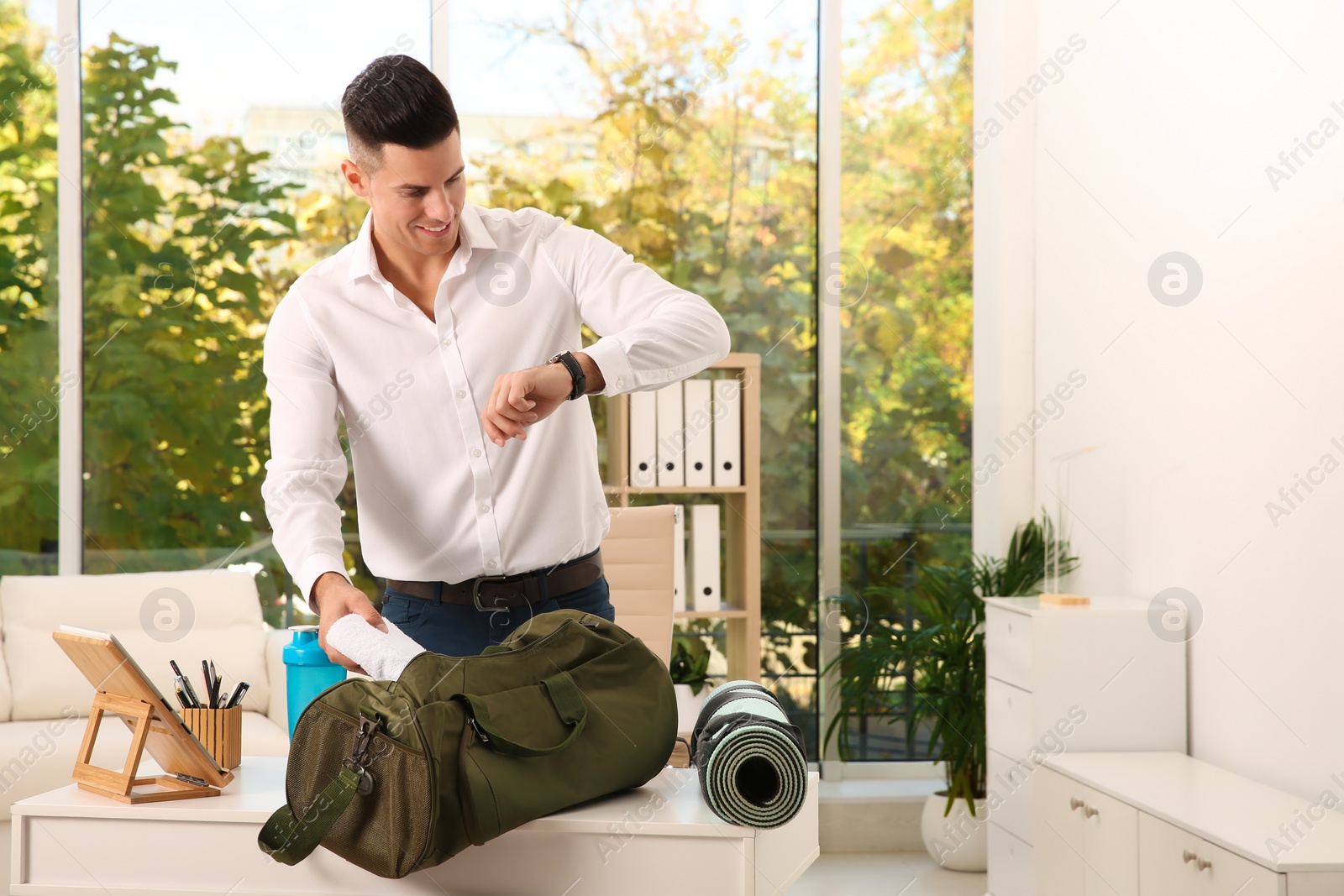 Photo of Businessman packing sports stuff for training into bag in office