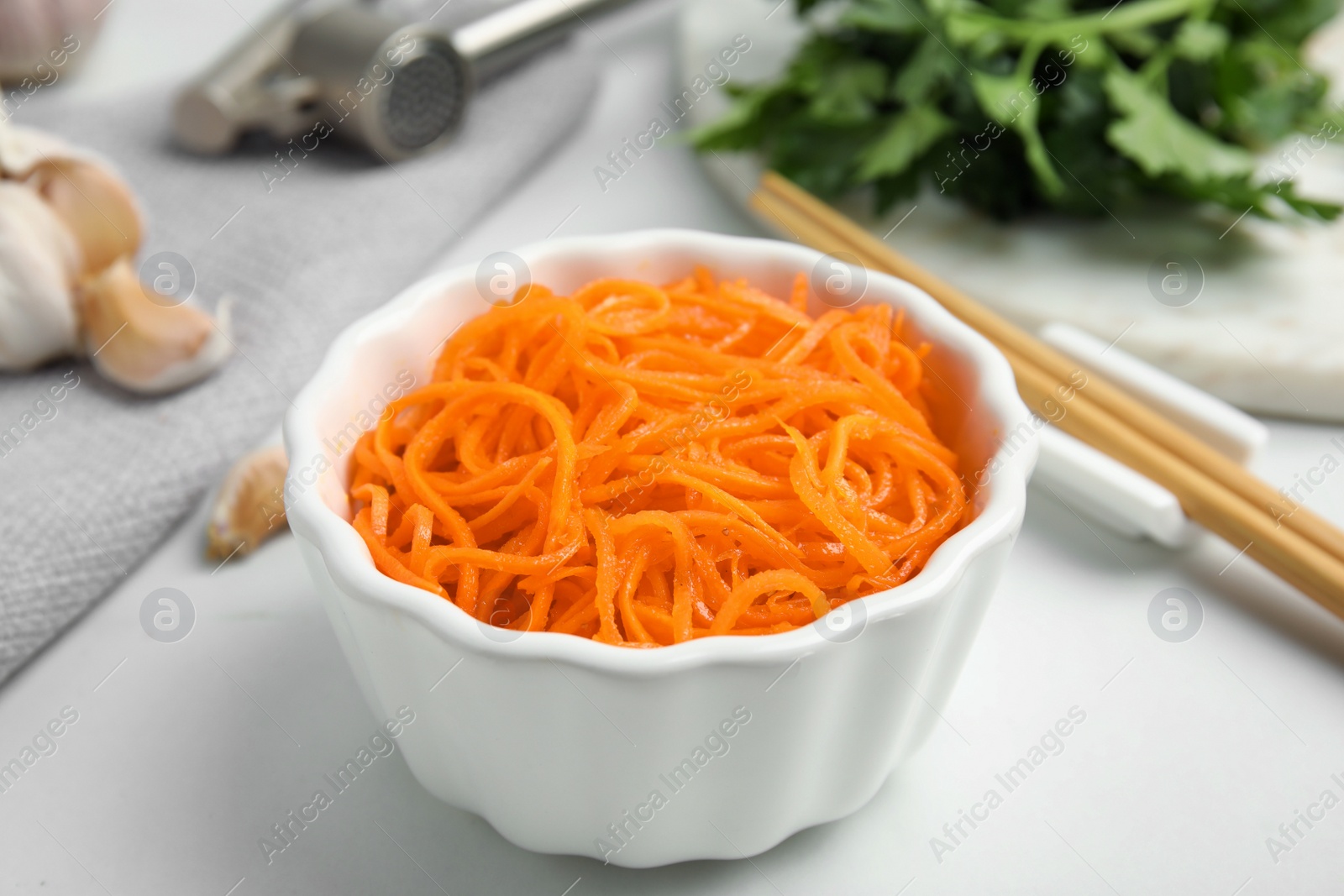 Photo of Delicious Korean carrot salad in bowl on white table