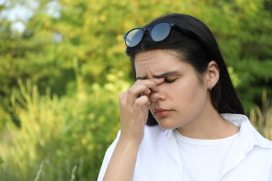 Photo of Young woman suffering from eyestrain outdoors on sunny day