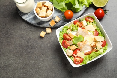 Photo of Delicious fresh Caesar salad in bowl on grey table, flat lay. Space for text