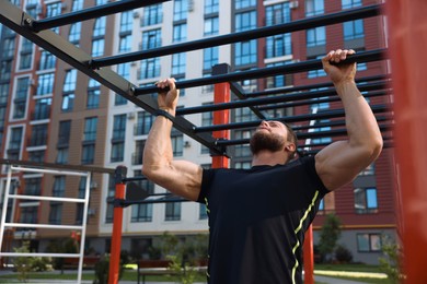 Young man training on monkey bars at outdoor gym