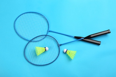 Photo of Rackets and shuttlecocks on light blue background, flat lay. Badminton equipment