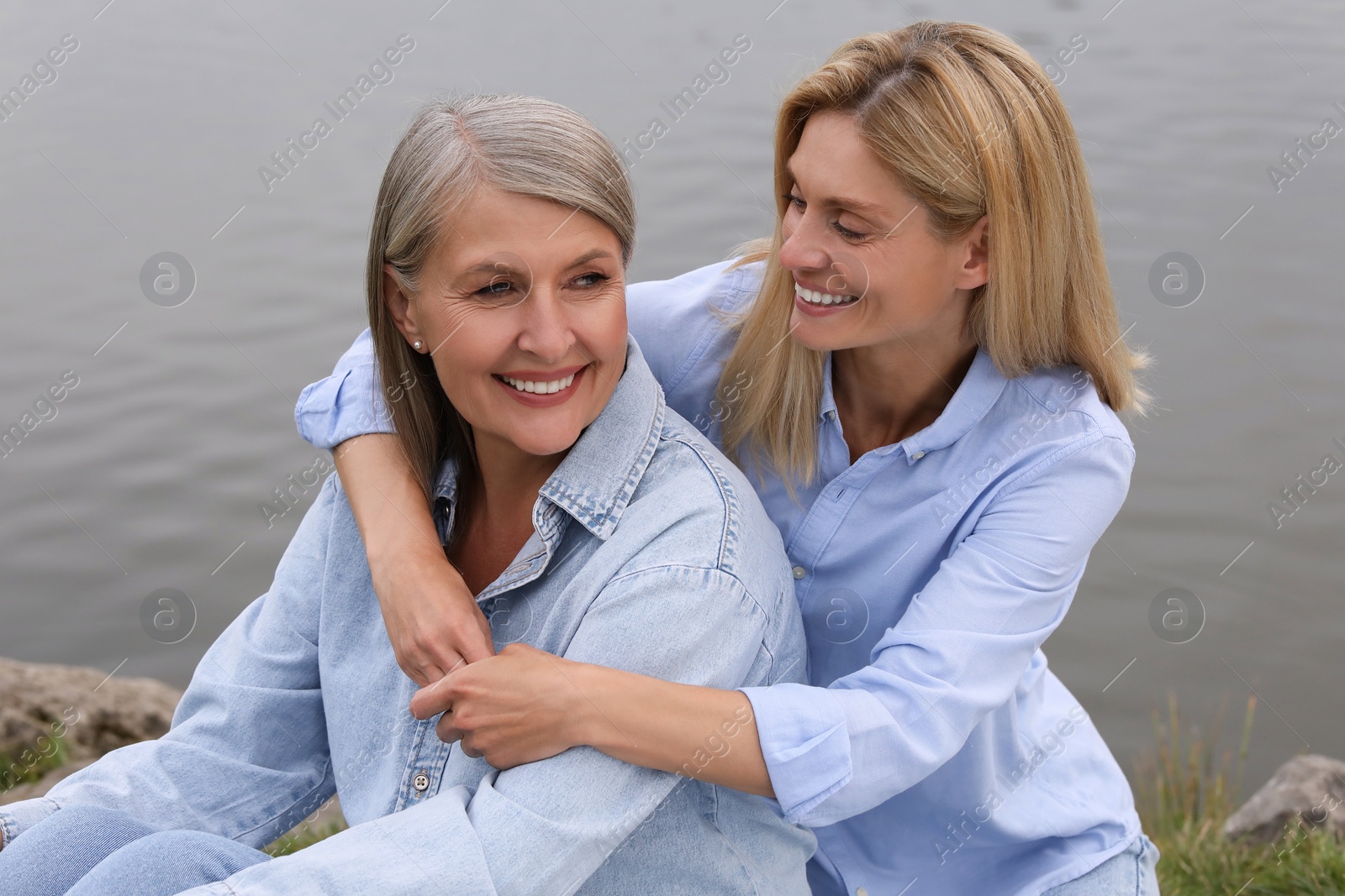 Photo of Happy mature mother and her daughter hugging near pond