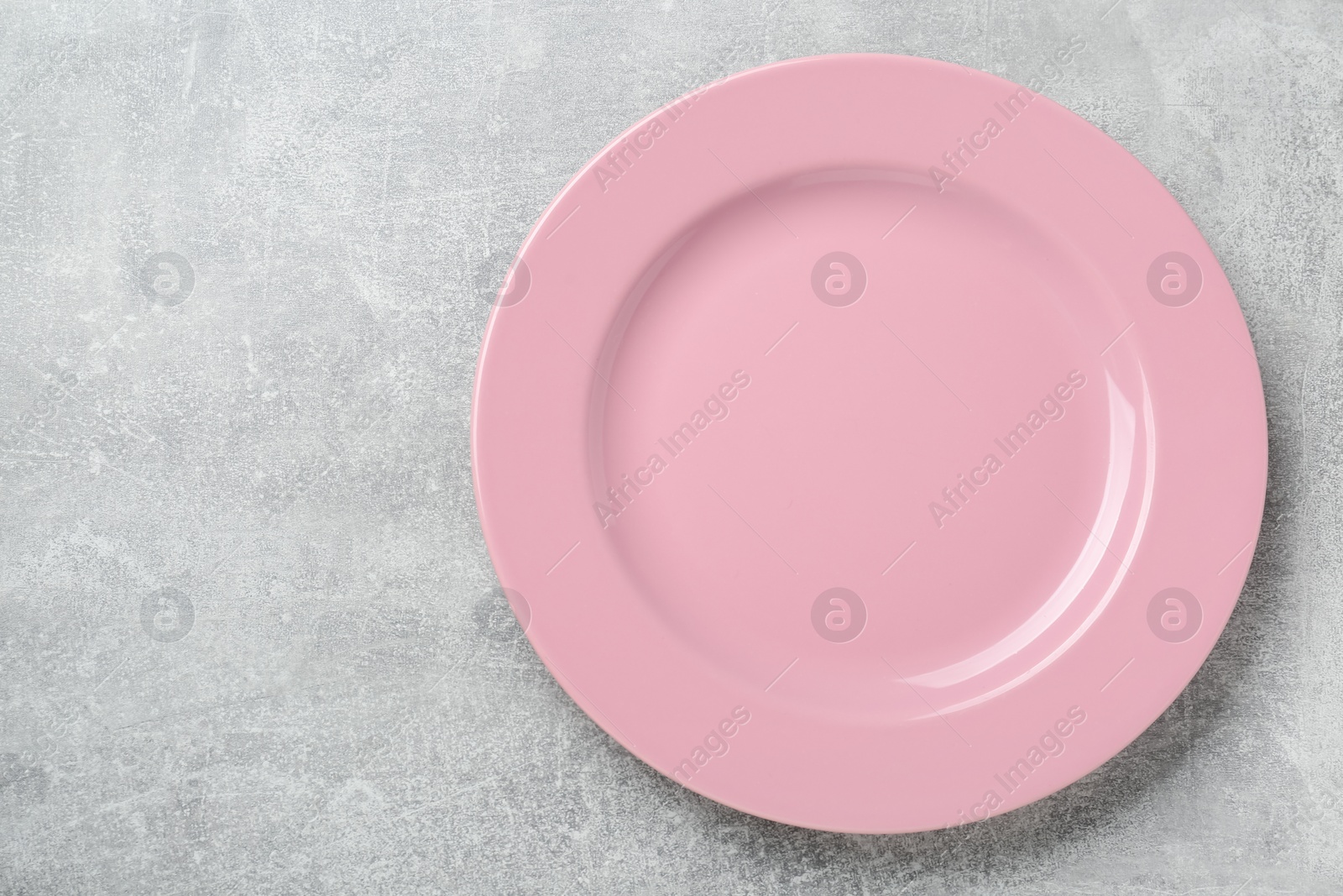 Photo of Empty pink ceramic plate on light grey table, top view. Space for text