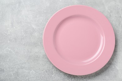 Photo of Empty pink ceramic plate on light grey table, top view. Space for text