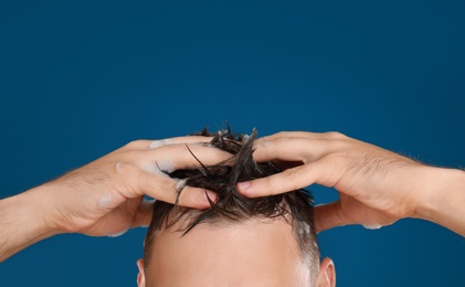 Photo of Man washing hair on blue background, closeup