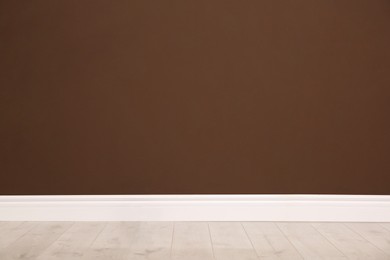Photo of Empty room with wooden floor and brown wall. Interior design
