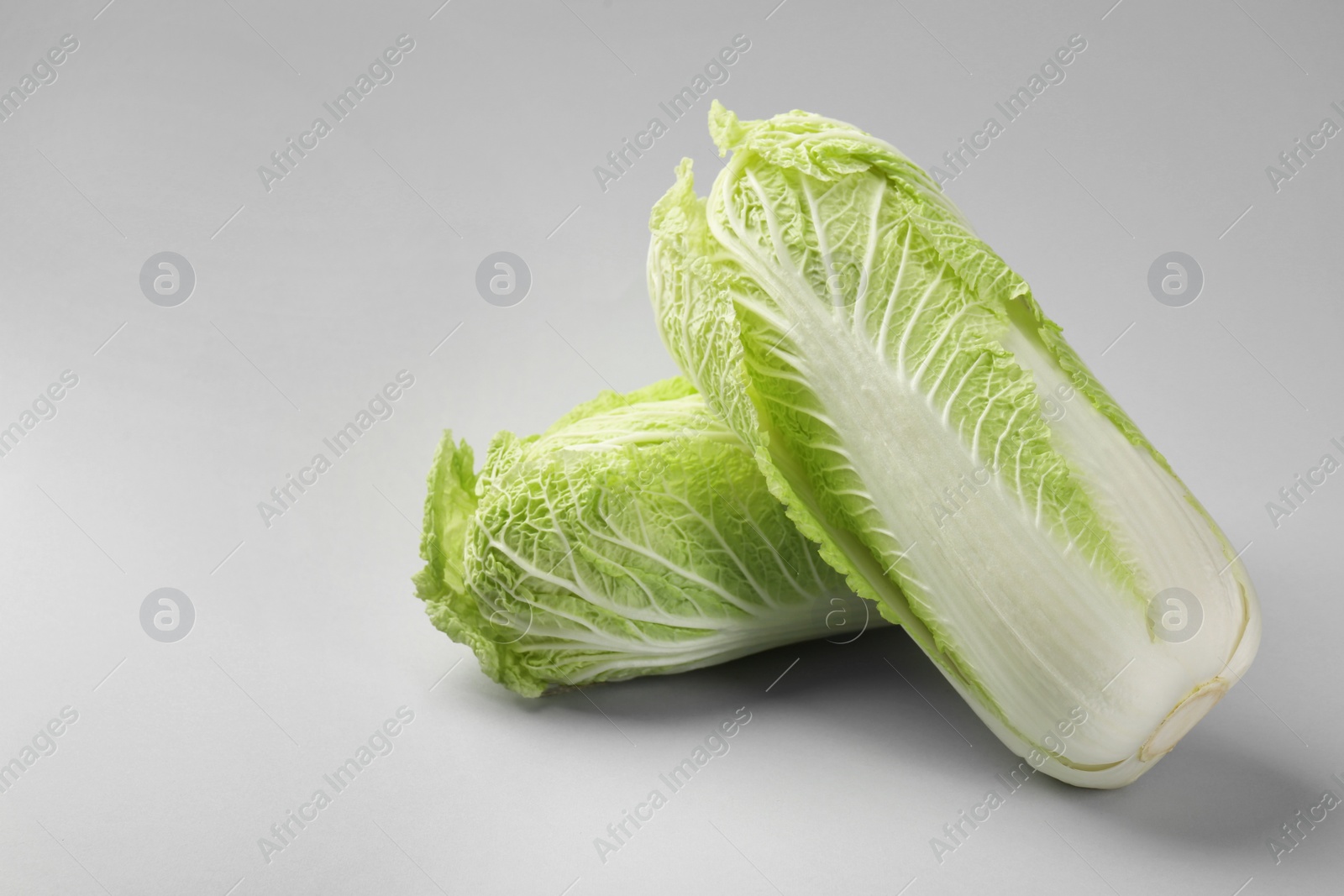 Photo of Fresh ripe Chinese cabbages on light grey background. Space for text