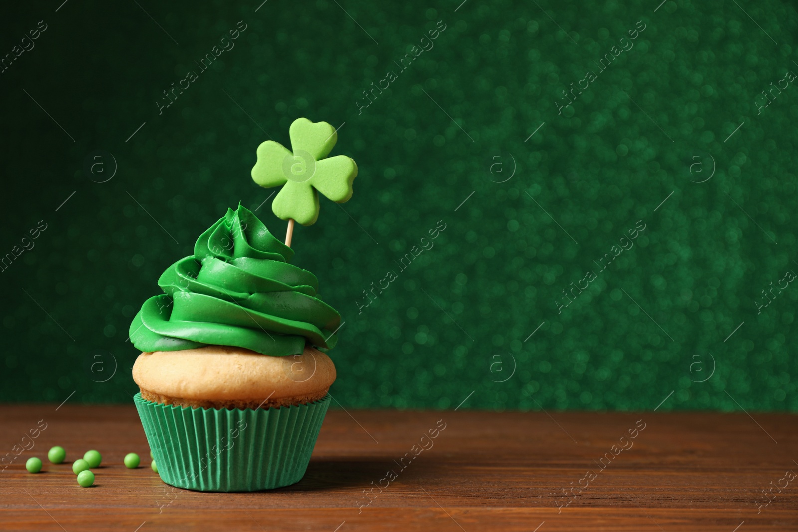 Photo of Delicious decorated cupcake on wooden table, space for text. St. Patrick's Day celebration