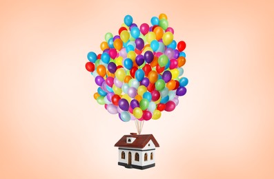 Image of Many balloons tied to model of house flying on pale orange background