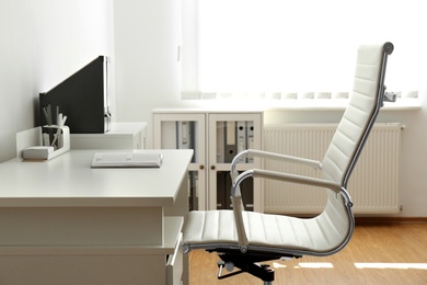 Photo of Stylish workplace interior with modern office chair and desk