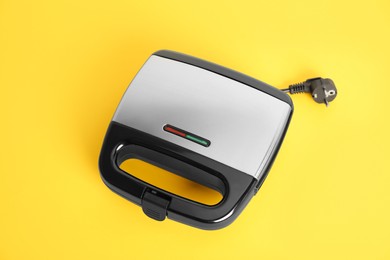 Photo of Modern electric sandwich maker on yellow background, above view