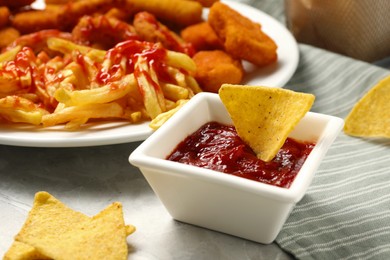 Different delicious fast food served with ketchup on light grey marble table, closeup