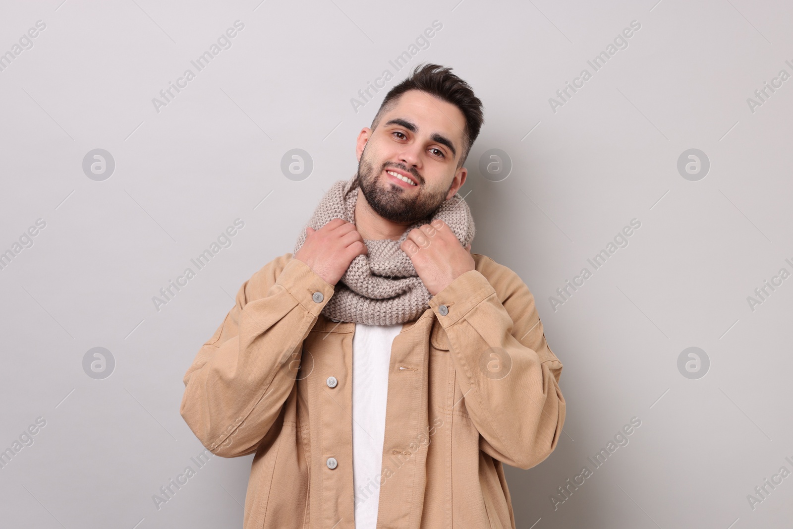 Photo of Smiling man in warm scarf on light grey background