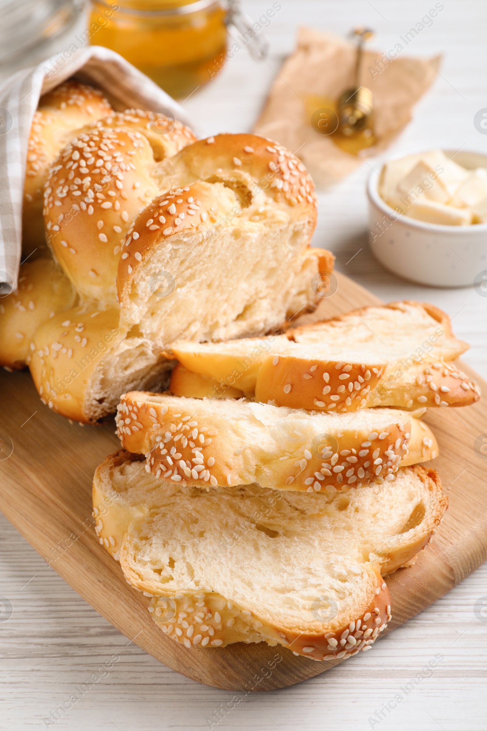 Photo of Cut freshly baked braided bread on white wooden table, closeup. Traditional Shabbat challah