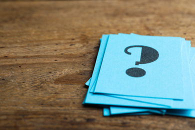 Photo of Blue paper cards with question mark on wooden background, closeup. Space for text
