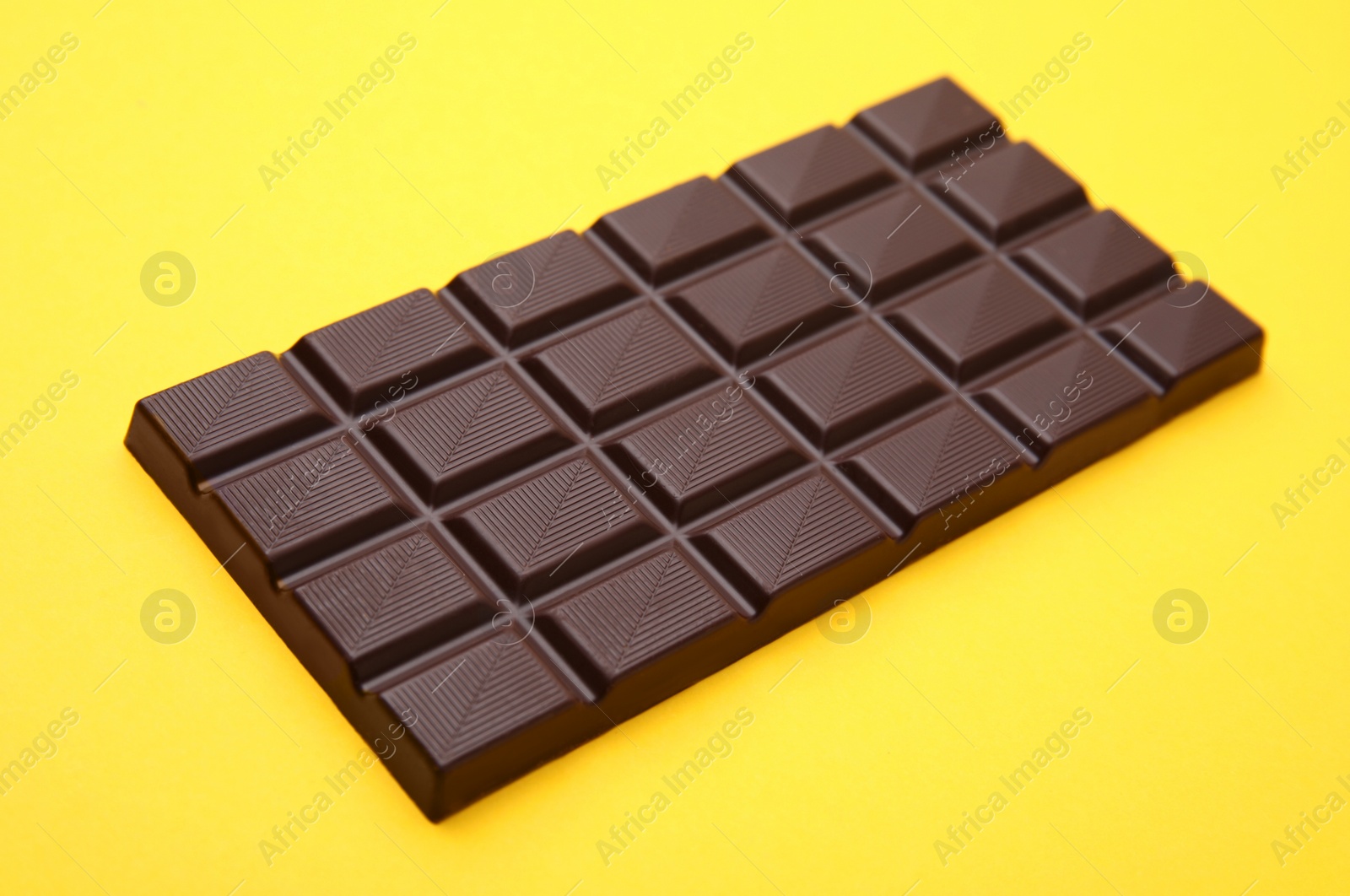 Photo of One tasty chocolate bar on yellow background