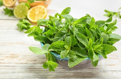 Bowl with fresh aromatic mint on table