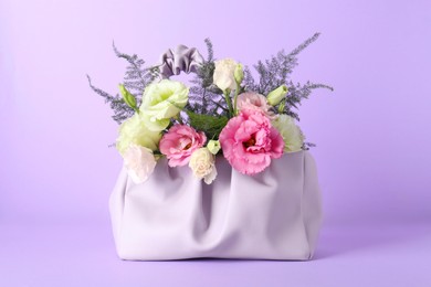 Photo of Stylish women's bag with beautiful flowers on violet background