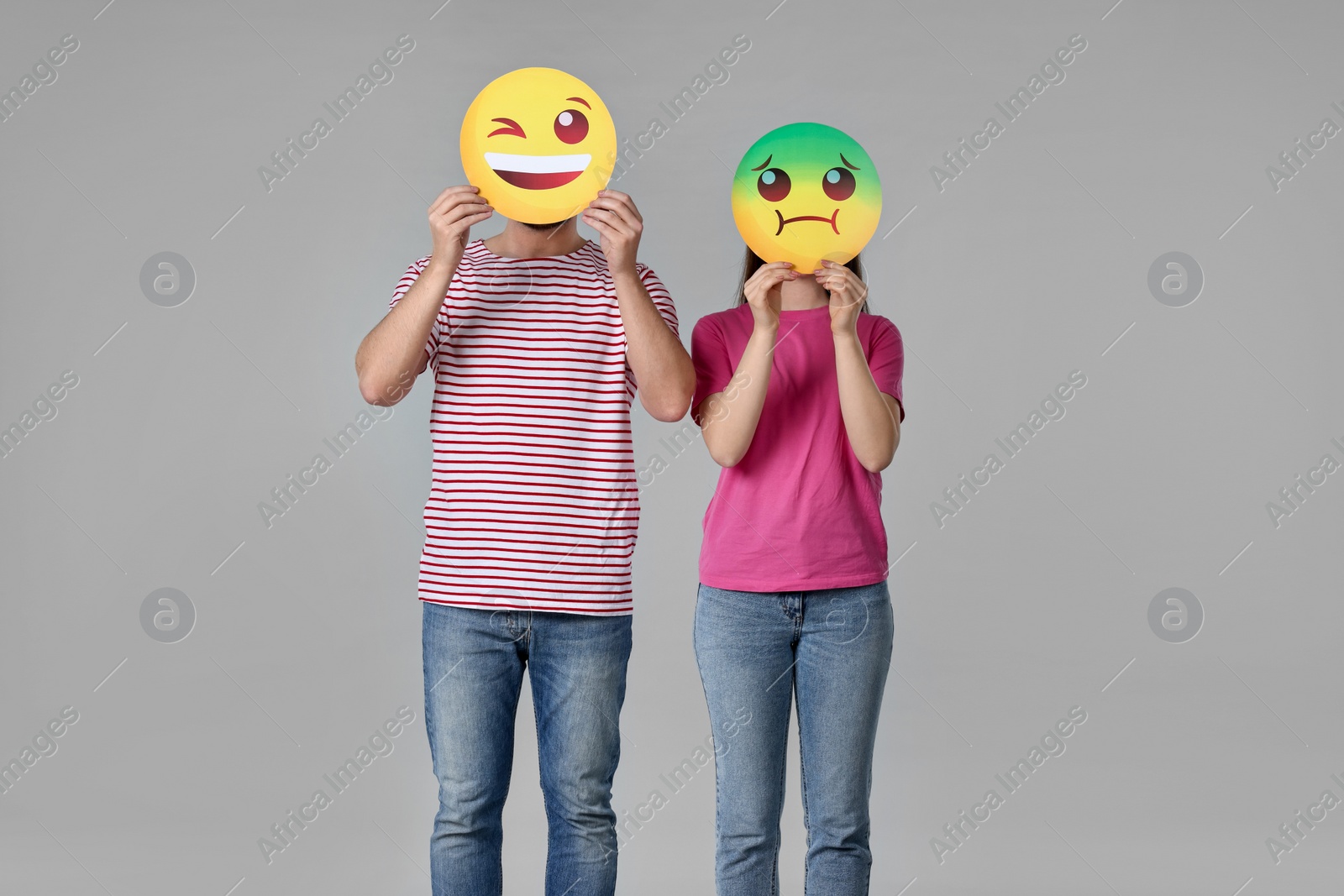 Photo of People covering faces with emoticons on grey background