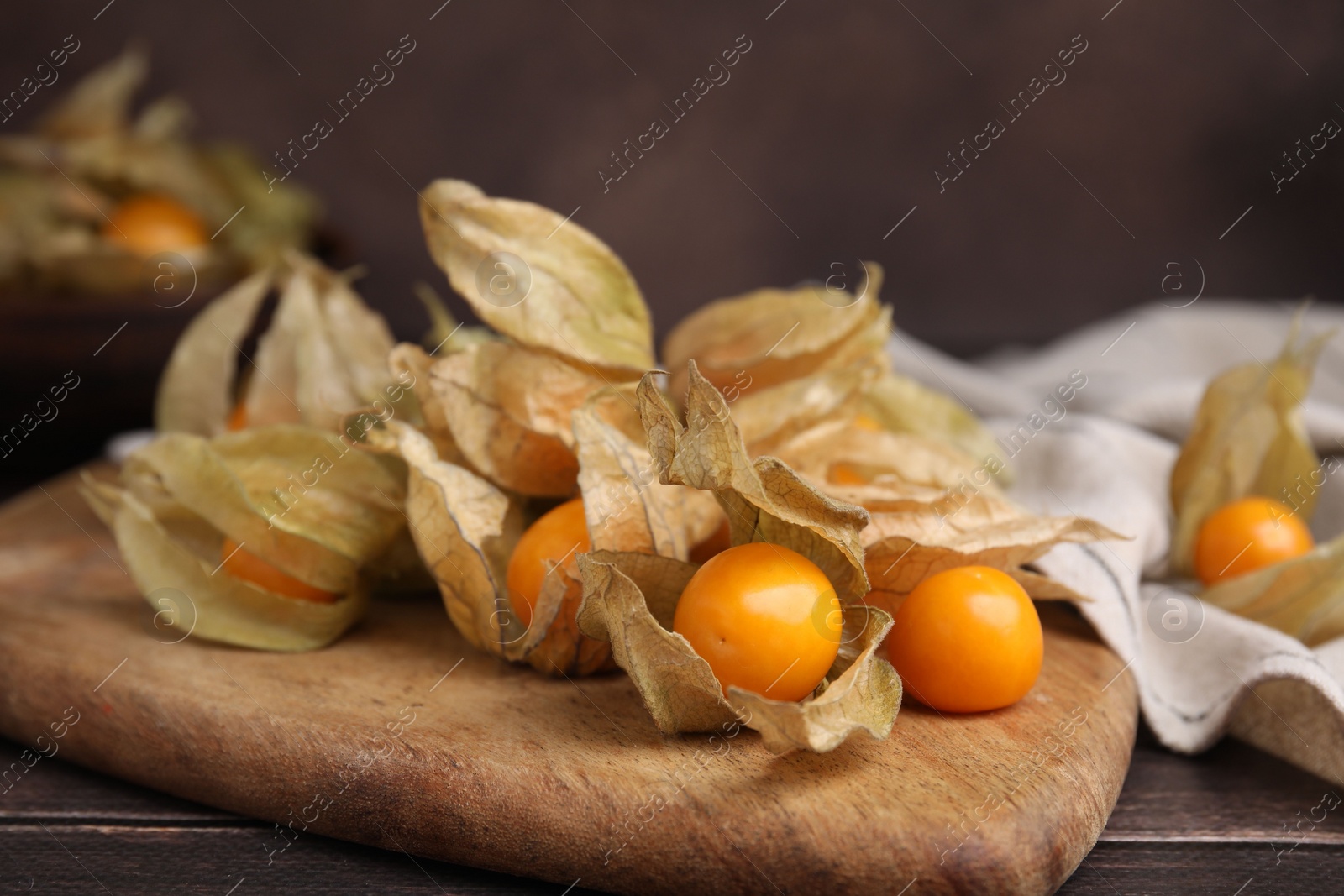 Photo of Ripe physalis fruits with calyxes on wooden table, closeup