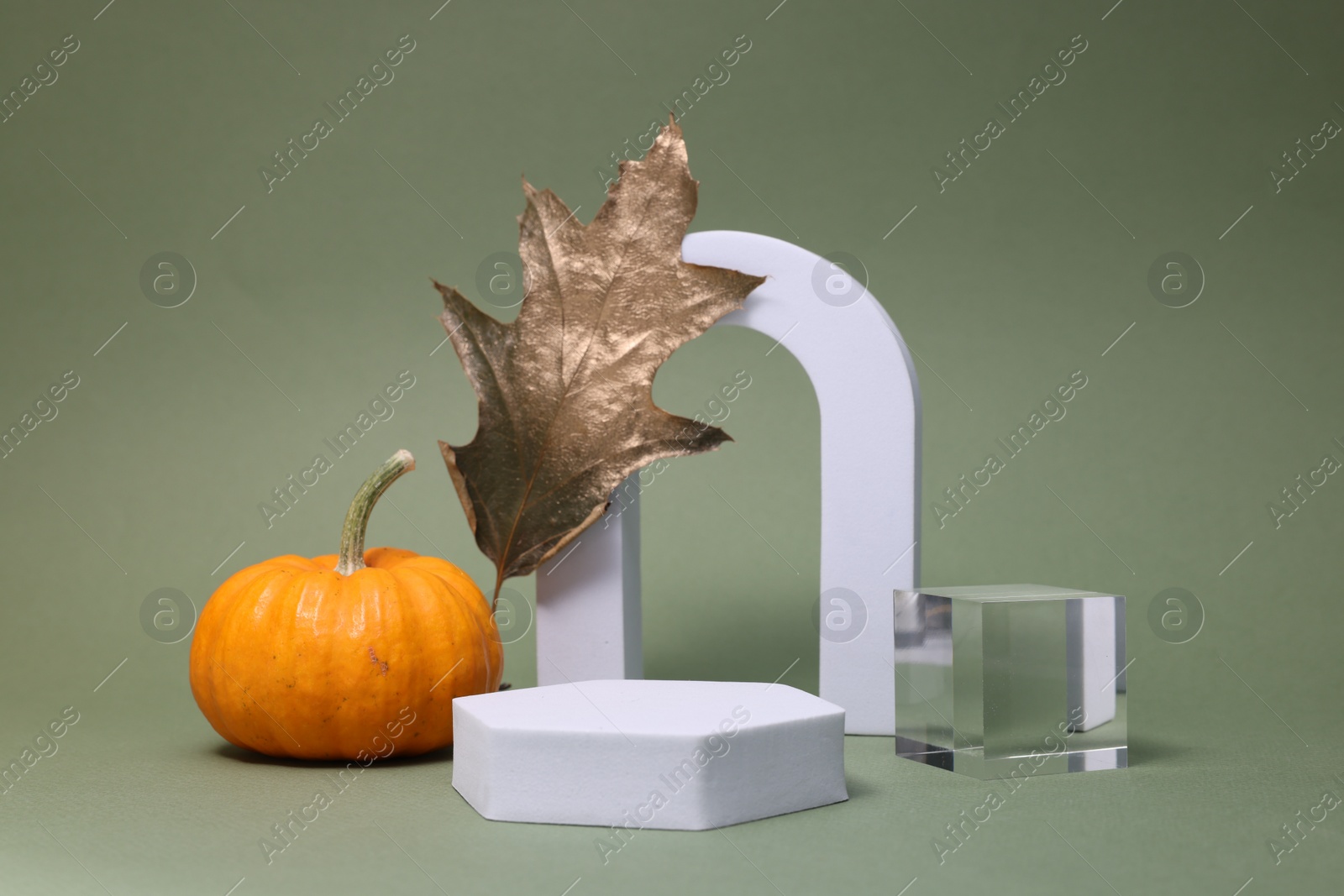 Photo of Autumn presentation for product. Geometric figures, pumpkin and golden leaf on olive background