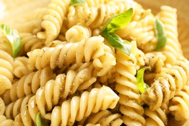 Photo of Delicious pesto pasta with basil leaves, closeup