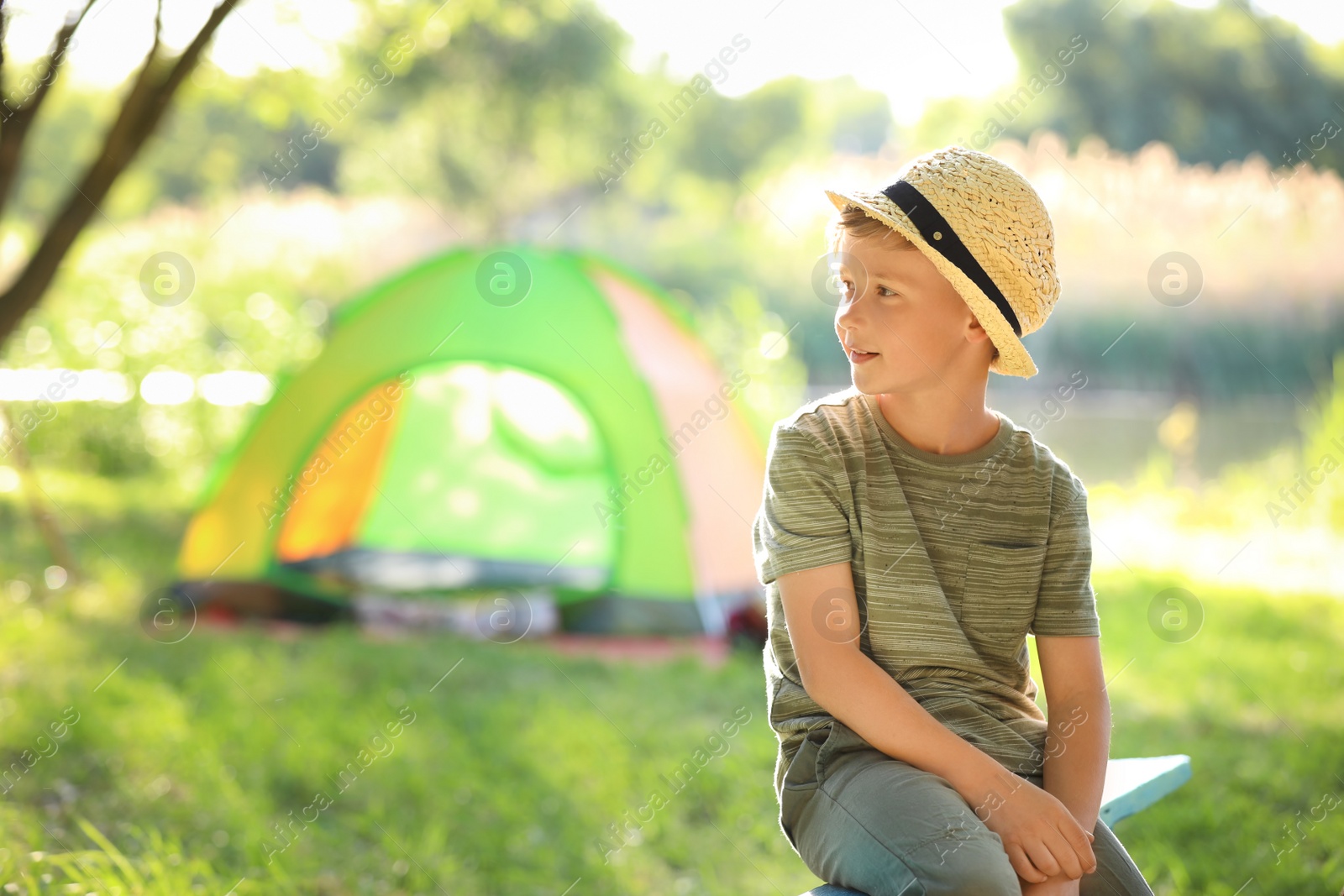 Photo of Little boy near tent outdoors. Summer camp