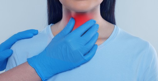 Endocrinologist examining thyroid gland of patient on light grey background, closeup. Banner design