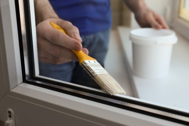 Man painting window frame at home, closeup