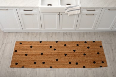 Stylish rug with dots on floor in kitchen, above view